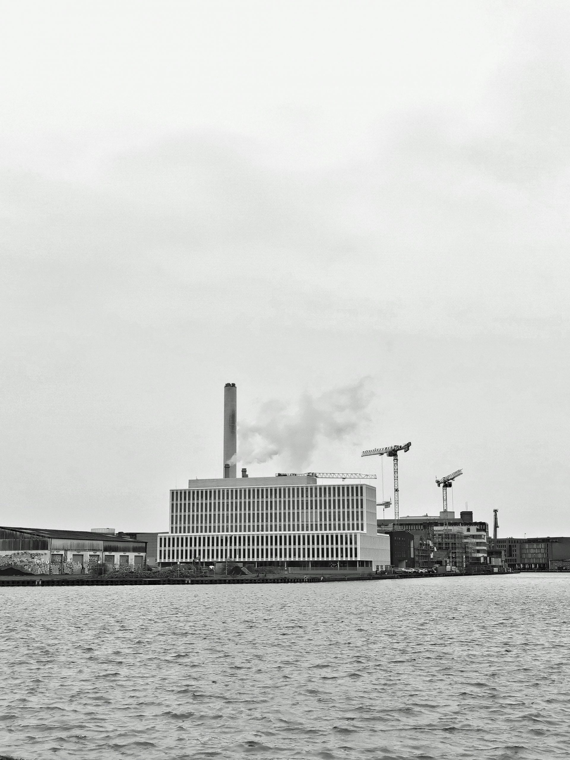 Factory in front of a large body of water.